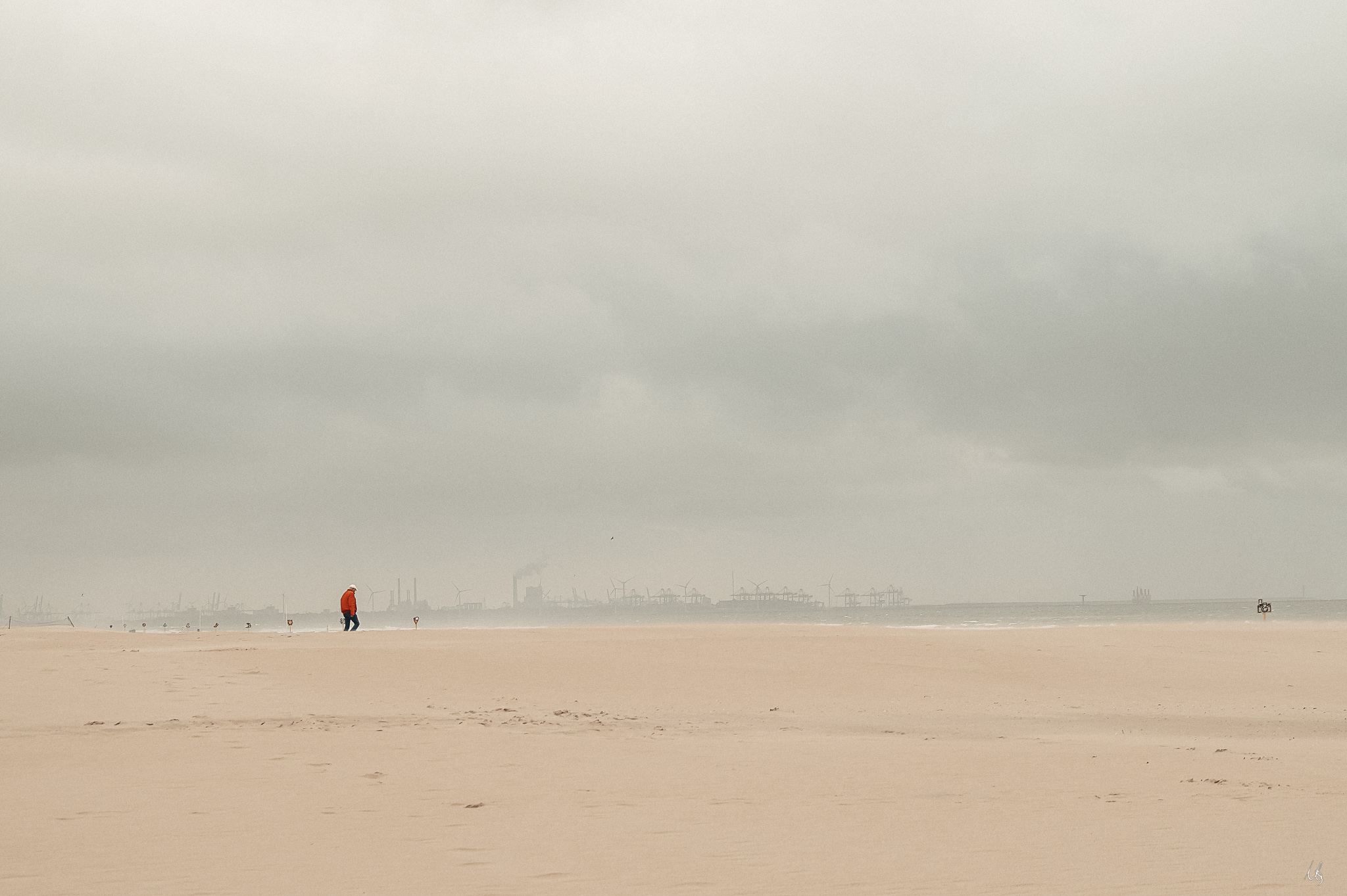 Person in roter Jacke am Strand