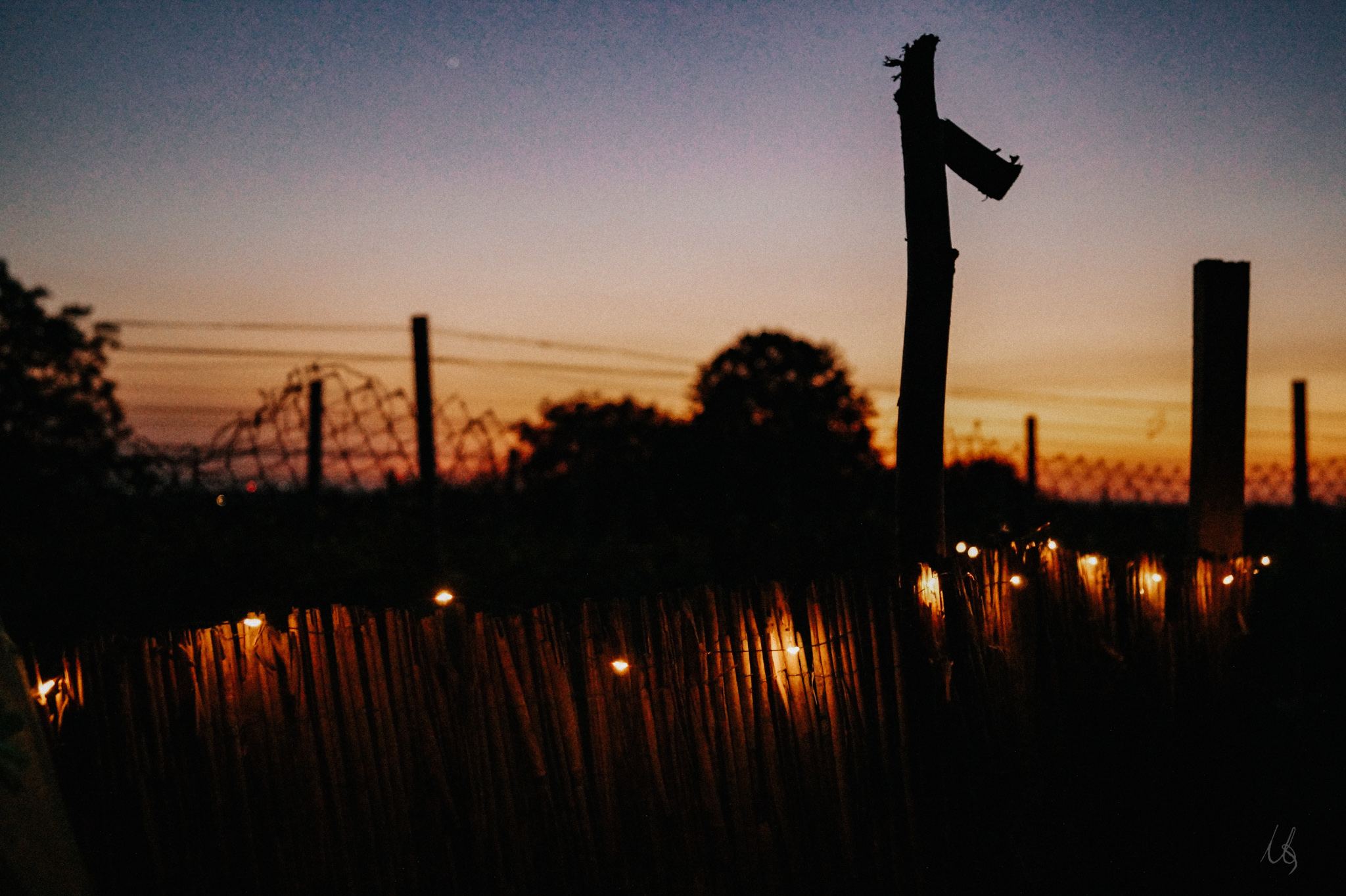 Lichterkette am Zaun im Sonnenuntergang